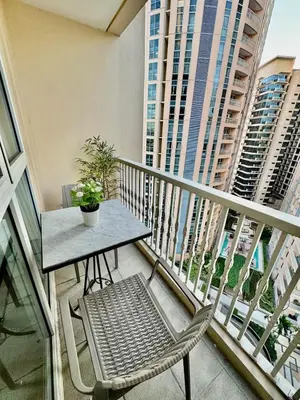 a table and a chair on a balcony with buildings at Cozy Home at Venice Luxury BGC in Manila