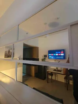 a reflection of a living room with a desk and a television at Shore Condotel Metro Staycation in Manila