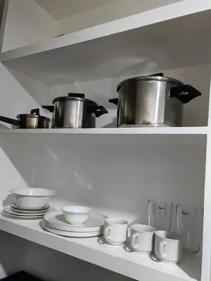 a shelf with pots and pans and plates in a kitchen at VM Staycation Tower 3 Grace Residence Taguig in Manila