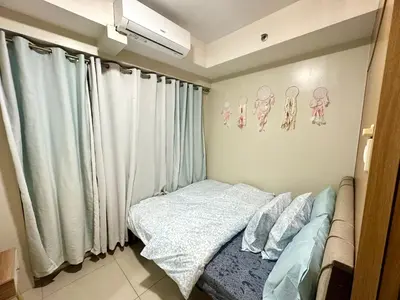 a small bedroom with a bed and curtains at Kathys Crib 11th flr at Shell Residence in Manila