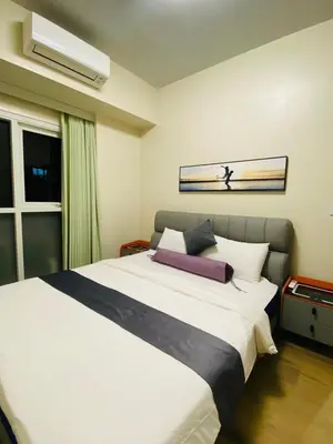 a bedroom with a large white bed and a window at Savvy Suites 3BR Near Okada in Manila