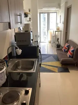 a kitchen with a sink and a living room at S Residence 3,Mall of Asia Area in Manila