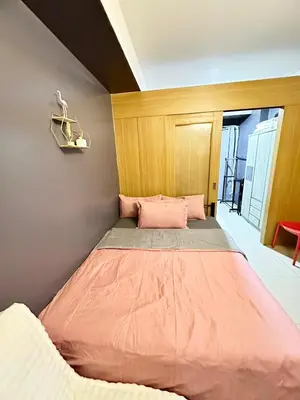 a bedroom with a large bed with pink sheets at Kathys Crib Family Suite Room at Shell Residence in Manila