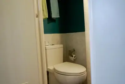 a bathroom with a white toilet and a green wall at Elegant Studio at Ortigas Business District, Pasig City in Manila
