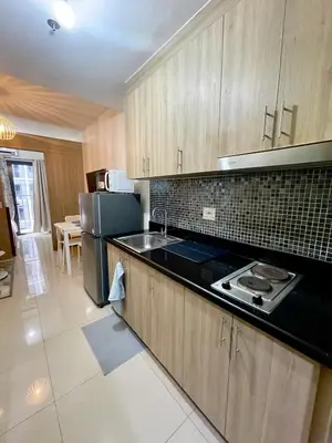 a kitchen with wooden cabinets and a black counter top at Vanilla Suites Mall of Asia Complex in Manila