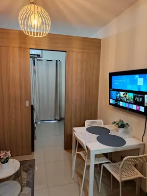 a dining room with a table and chairs and a tv at Vanilla Suites Mall of Asia Complex in Manila