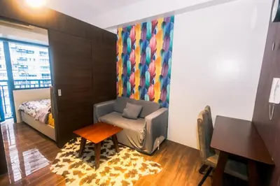 a room with a chair and a bed and a table at Cozy Peacock hideaway Stylish Makati Condo 300 Mbps Gym Swim Park in Manila