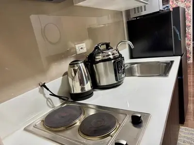 a kitchen with a stove with a tea kettle and a toaster at Galloping Suite Executive Makati Suite Gym Swim Park 300 Mbps in Manila