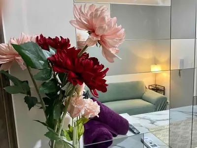 a vase filled with red and pink flowers on a table at Jazz Air Rooftop Penthouse Bar Gym Swim Park 300 Mbps Air 4034 in Manila