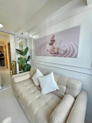 a white couch in a living room with a rabbit painting at Shore 3 Tower 4 Amenity View Pasay in Manila