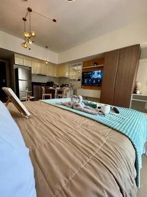 a large bed in a room with a kitchen at Chic Staycation with Balcony,few step in venice mall in Manila