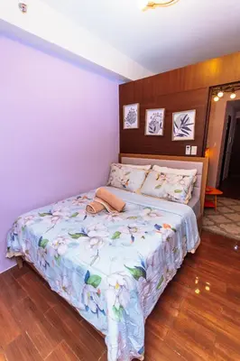 a bedroom with a bed with a floral bedspread at Chic Floating Penthouse Makati Gym Air condo gym swim park 300MB in Manila