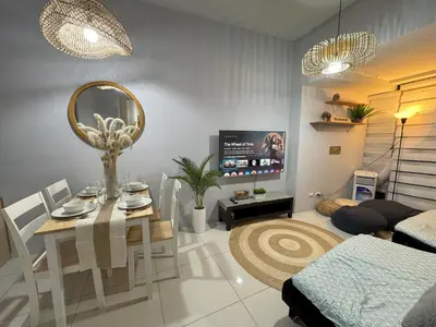 a living room with a dining table and a tv at Cozy 3 Bedroom in Uptown Parksuites - Near Mall, Restaurants and Supermarket in Manila