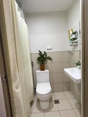 a bathroom with a toilet and a sink with a plant at Filed Residences Hotel Apartment in Manila