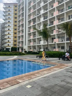 a woman playing in a pool with a tennis racket at Field Residences Condo Hotel in Manila