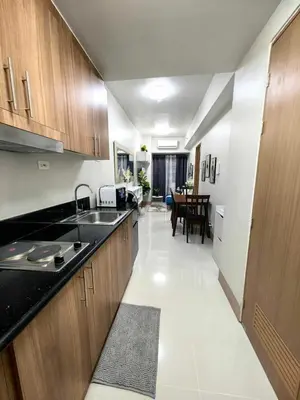 a kitchen with wooden cabinets and a dining room at Luxurious Condo Near SM MOA in Manila