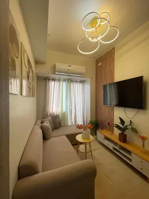 a living room with a couch and a flat screen tv at Field Residences Condo Hotel in Manila