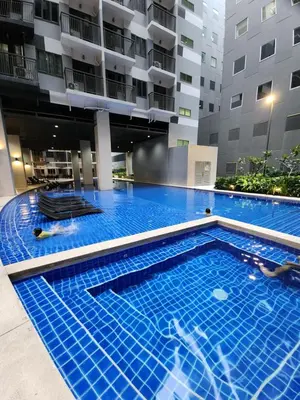 a large swimming pool in front of a building at 1BR with balcony Condotel in MOA Complex, Entertainment City, near NAIA, free wifi, netflix in Manila