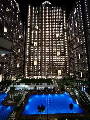 a large building with a large blue pool in front of it at SG Urban Staycation in Manila