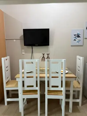 a dining room table with two white chairs and a television at Relaxing shining sunrise in Manila