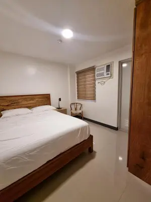 a bedroom with a large white bed and a chair at Flat 35, Unit 3C in Manila