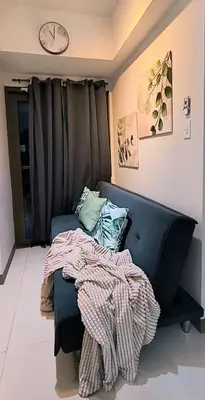 a living room with a couch and a clock on the wall at El Marhabea Crib in Manila