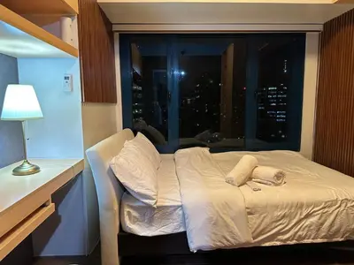 a bedroom with a bed with a window with a city at 1BR Air Residences condo, Ayala Ave, Makati in Manila