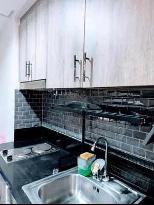 a kitchen with a stainless steel sink and white cabinets at Mall of Asia Condo Pasay in Manila