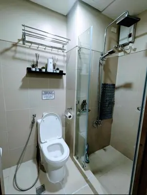 a bathroom with a shower and a toilet with a glass shower stall at Mall of Asia Condo Pasay in Manila