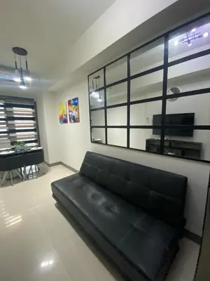 a black couch in a living room with a window at The Skycabin at S Residences in Manila