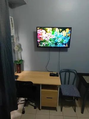 a computer desk with a television on a wall at Berto's High Speed Wifi in Manila