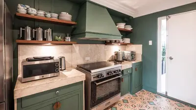 a kitchen with green cabinets and a stove and microwave at MIRANAMIN NEST Elegant Home, Indoor Plunge Pool, Pet-Friendly, with Rooftop, Kitchens, Self-Service Breakfast - Ideal for Reunions, Team Building, Intimate Gatherings in Manila