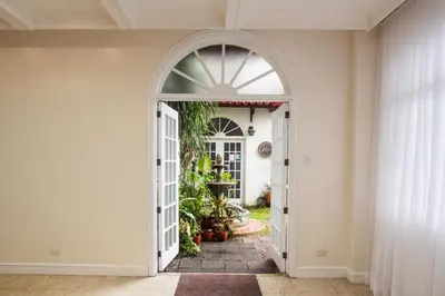 an arched doorway into a home with an archway at MiraNamin Nest CALACHUCHI - Cozy Room in Historic Home - Indoor Plunge Pool, Petite Desk, Garden View with Balcony, Self-Service Breakfast, Guest Kitchen, Rooftop, Pet-Friendly in Manila