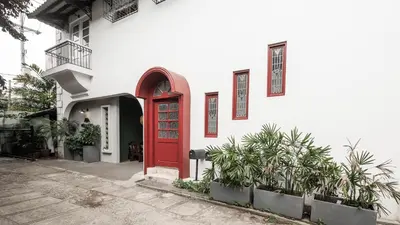 a red door on a white building with plants at MiraNamin Nest KAMANTIGI - Two Bed Suite in Historic Home with Luxury Indoor Plunge Pool, Garden Access, Self-Service Breakfast, Guest Kitchen, Pet-Friendly in Manila
