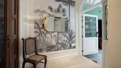a hallway with a chair and a wallpaper with palm trees at MiraNamin Nest KAMANTIGI - Two Bed Suite in Historic Home with Luxury Indoor Plunge Pool, Garden Access, Self-Service Breakfast, Guest Kitchen, Pet-Friendly in Manila