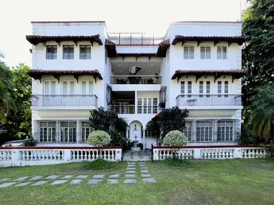 a white building with a yard in front of it at MiraNamin Nest KAMANTIGI - Two Bed Suite in Historic Home with Luxury Indoor Plunge Pool, Garden Access, Self-Service Breakfast, Guest Kitchen, Pet-Friendly in Manila