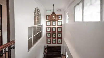a hallway with a staircase with pictures on the wall at MiraNamin Nest LIRYO and LANTANA - Luxury Residence in Unique Historic Home - Indoor Plunge Pool, Self-Service Breakfast, Garden View, Rooftop, Private Kitchen in Manila