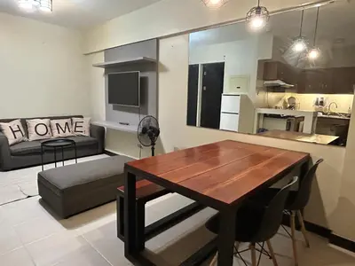 a kitchen and living room with a table and a couch at The Mindful Home - 2BR Cozy Condo near NAIA in Manila