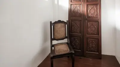 a chair sitting in front of a wooden door at MiraNamin Nest LIRYO - Family Suite in Unique Historic Home with Indoor Plunge Pool, Garden Access, Self-Service Breakfast, Guest Kitchen in Manila