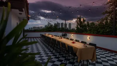 a long table with chairs and lights on a balcony at MiraNamin Nest ROSAL - Garden View Suite in Unique Historic Estate with Indoor Plunge Pool, Self-Service Breakfast, Guest Kitchen in Manila