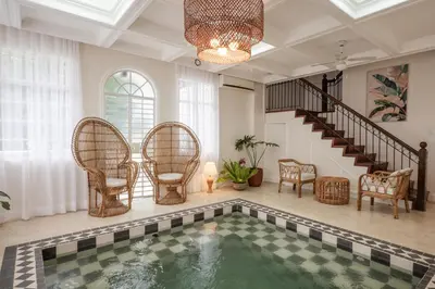 an indoor pool in a house with chairs and a staircase at MiraNamin Nest ROSAL - Garden View Suite in Unique Historic Estate with Indoor Plunge Pool, Self-Service Breakfast, Guest Kitchen in Manila