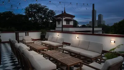 a row of chairs and tables on a patio at MiraNamin M A P I L I G - Private Suite in Historic Home with Unique View, Self-Service Breakfast, Indoor Plunge Pool, Rooftop, Shared Kitchen in Manila