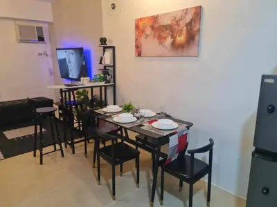 a dining room with a table and chairs and a television at Urban Metro Escape in Pasig City in Manila