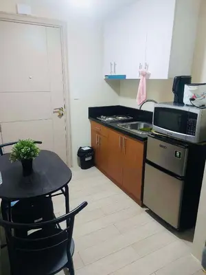 a small kitchen with a table and a microwave at Jennie's Lucky 5M Suite in Manila