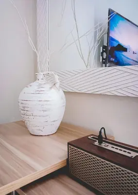 a white vase sitting on a wooden shelf next to a tv at LuxeStaysMnl Cozy Japandi Netflx Pool 400mbps in Manila