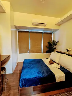 a bedroom with a large bed with a blue blanket at 1 bedroom Cozy Escape in Manila