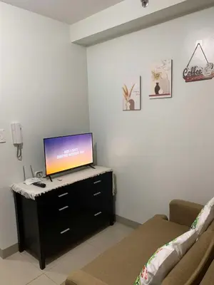 a living room with a flat screen tv on a dresser at Shore2 tower2 11th floor, unit 1122 VSV Luxury Family Suite staycation Moa in Manila