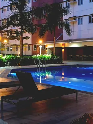 a swimming pool with a chair in front of a building at Kaunis Hive Hope Residences in Trece Martires