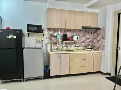 a kitchen with a black refrigerator and wooden cabinets at A cozy condo within the center of Manila in Manila