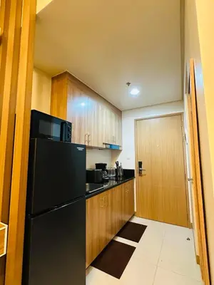a kitchen with a black refrigerator and wooden cabinets at RED RESIDENCES Makati in Manila